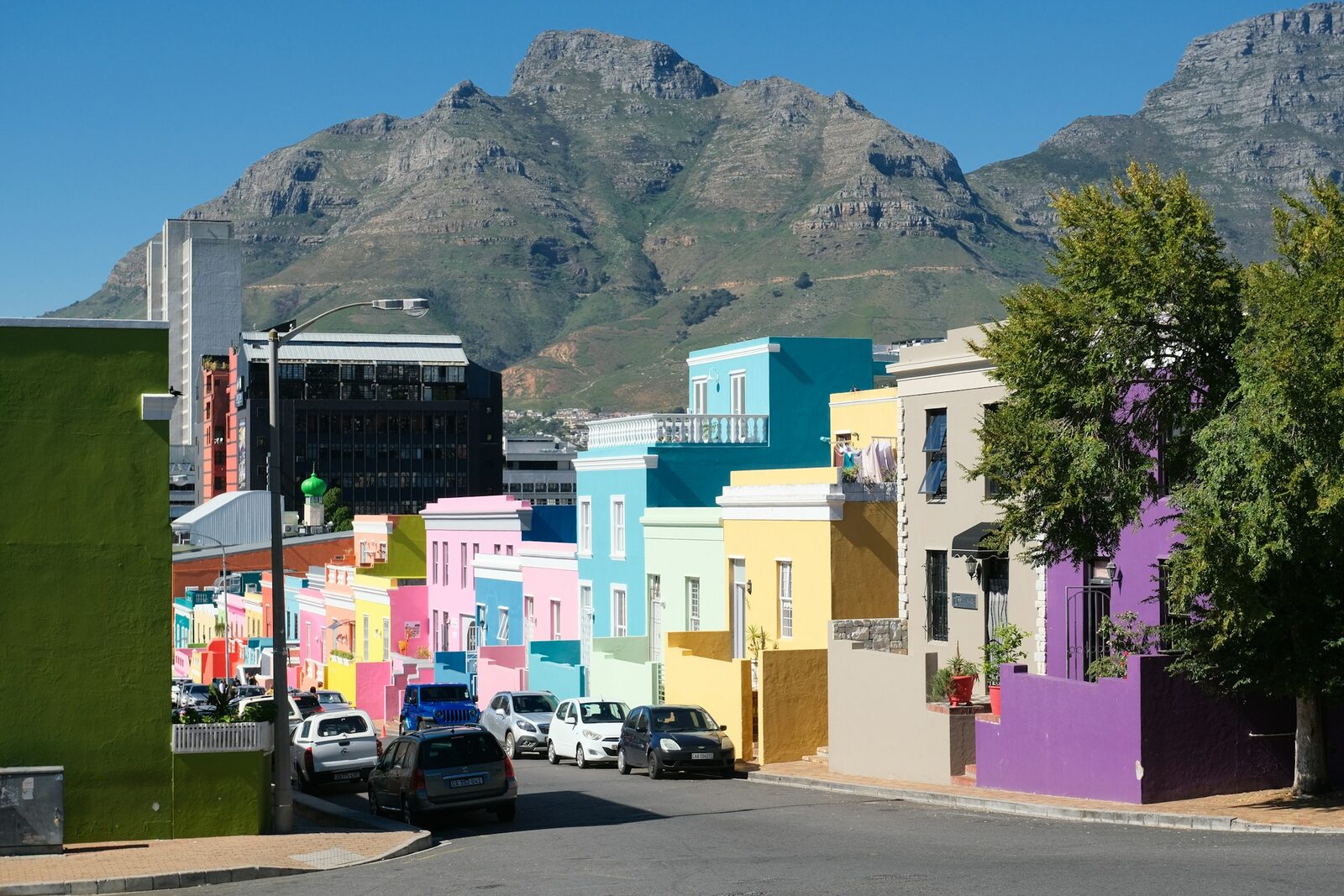 A Cape Town street of brightly painted houses with Table Mountain rising behind it.