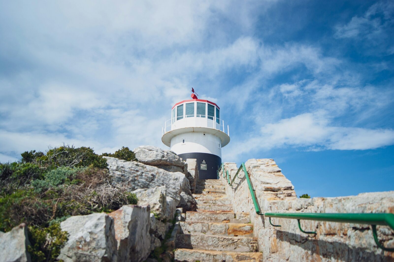 The old lighthouse at Cape Point standing on a rocky headland above the Atlantic Ocean.